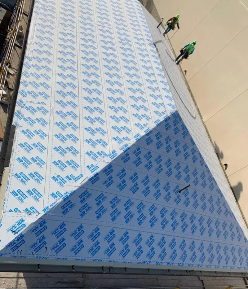 Professional roofers installing underlayment on a metal roof in Pratt